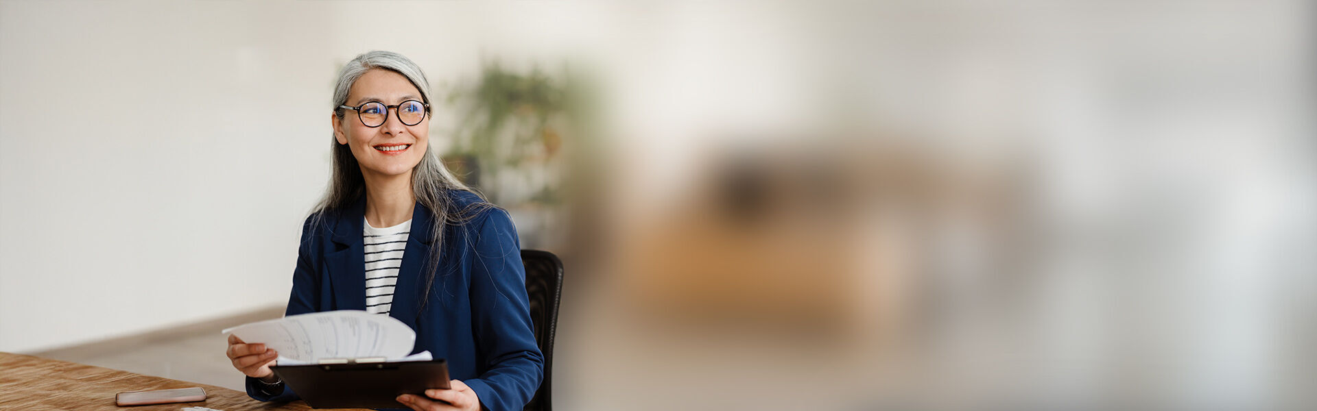 eine Frau in der Brille sitzt an einem Schreibtisch mit einem Buch